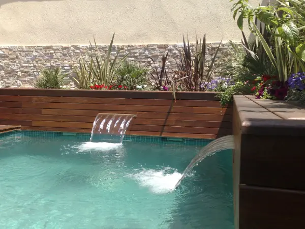 Piscina termal al aire libre con vapor ascendente entre rocas naturales y vegetación