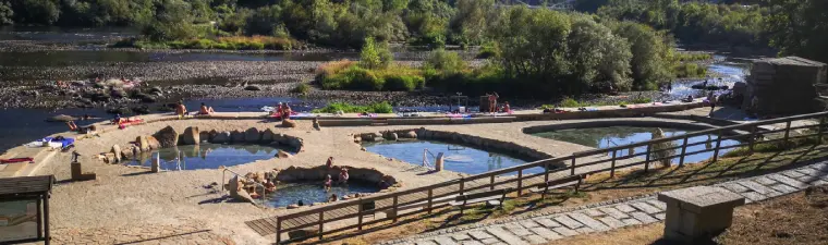 Balneario de aguas termales en Ourense con arquitectura de piedra gallega y vapor ascendente